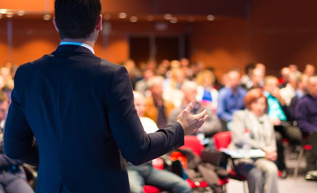 looking at audience and male speaker's back